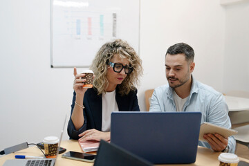 Business colleagues collaborating on laptop and tablet during meeting