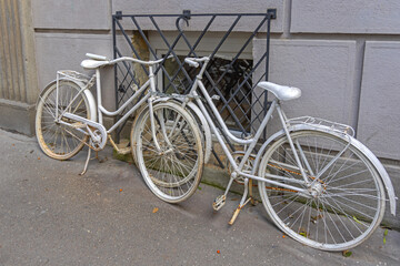 Two Old White Bicycles Chained to Window Bars at Street Decor
