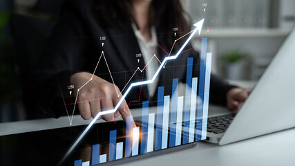 A business professional interacts with digital data trends on a laptop in a modern office. The graphics highlight upward growth and success in analytics and finance. Scalp