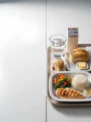 Hospital meal tray placed on the right side of a bright table, simple portions of balanced food, large clean white surface on the left serving as negative space for medical or nutrition messaging.