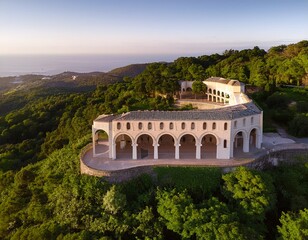 Fototapeta premium aerial view of a unique building with arches on the side of a hill surrounded by lush vegetation