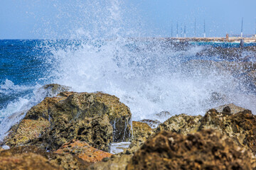 Beautiful view of powerful waves crashing on rocky coast of Caribbean Sea with blue sky on background. Curacao.