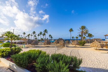 Beautiful view of hotel beach area with palm trees straw umbrellas and beach volleyball court by Caribbean Sea. Curacao.