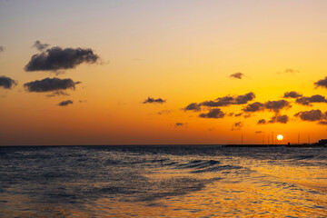 Beautiful view of golden sunset over calm Caribbean Sea with gentle waves and dramatic clouds. Curacao.