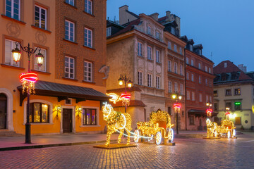 Illuminated Christmas carriage decorations on a cobblestone street in Old Town Warsaw Poland