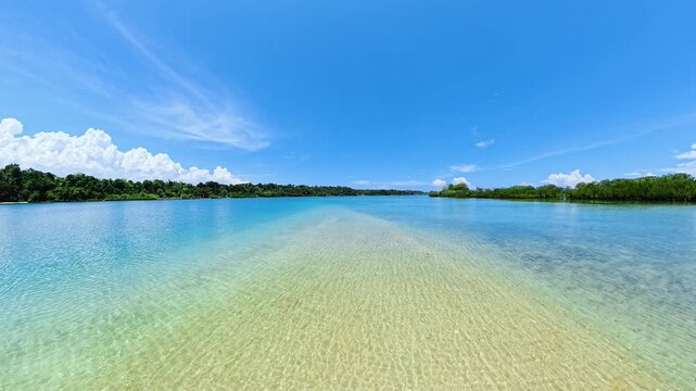 Transparent shallow water extending towards the distant lush coastline. Turtle Island, Negros, Philippines.