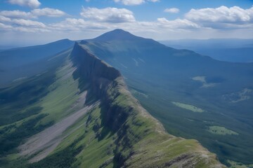 Aerial view of a rugged mountain range with lush greenery and cloudy skies