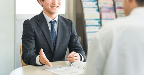 A young Asian businessman negotiating, serving and meeting with a male customer (car/insurance)