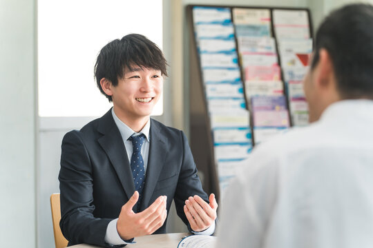 A young Asian businessman negotiating, serving and meeting with a male customer (car/insurance)