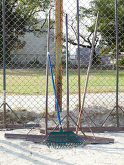 公園の野球場の柵の横にあるたくさんのグランドレーキの様子