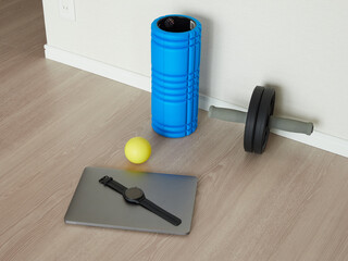 家のリビングの床にあるノートパソコンと運動用のローラーなどのエクササイズ用品