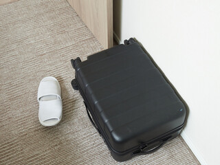 ホテルの客室の床にあるスーツケースとホテル用スリッパの様子