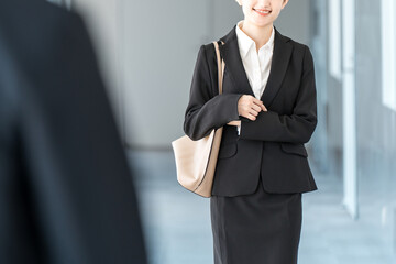 A businesswoman in a suit walking down an office corridor (going to work, commuting to work)