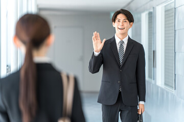 A businessman in a suit walking down an office corridor (going to work, going to work, greeting)