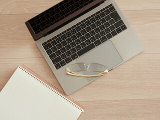 机の上にあるノートブックとメガネとノートパソコンの様子