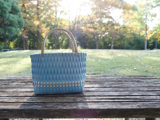 秋の公園のベンチの上にある編みカバンの様子