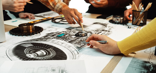 A dynamic engineering meeting showcasing hands engaged in drawing and discussing intricate mechanical designs, highlighting teamwork and creativity in innovation. SACTR