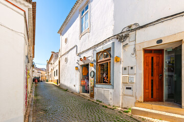 A whitewashed cobblestone street through the historic old town of Lagos, Portugal, in the Algarve region of Southern Portugal.