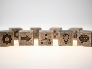 Workflow strategy icons on wooden cubes aligned using shallow focus and subtly glowing white environment