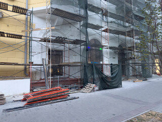 Workers prepare building materials at a construction site with scaffolding and tools in the evening