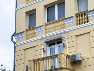 A yellow building with decorative features has a balcony and windows