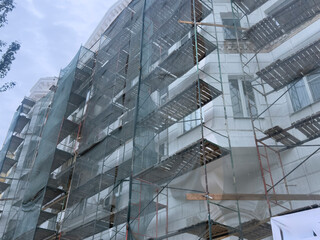 Workers prepare to renovate the building wrapped in scaffolding and mesh near the street