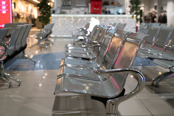 Several metal benches are arranged neatly in an airport terminal. The area is mostly empty