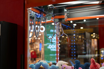Claw machine shows stuffed toys displayed under bright lights in a shopping center