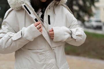 A woman is adjusting her winter coat outdoors as she prepares for cold weather