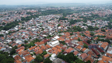 Aerial view of a densely populated residential area with orange rooftops and lush greenery