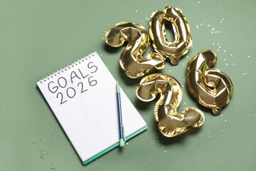 Notebook with text GOALS 2026, pen and balloons on green background