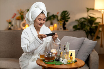 Asian adult woman taking photo of spa relaxation wellness items in cozy home living room enjoying self care evening