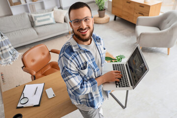 Young man using laptop to search for tickets online at home
