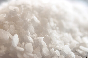 Macro shot of granulated white sugar crystals forming irregular clumps.