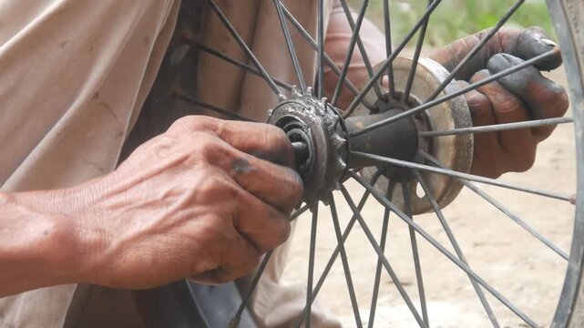 The mechanic's hands were dirty with oil and grease while repairing the bicycle axle. bicycle wheel service