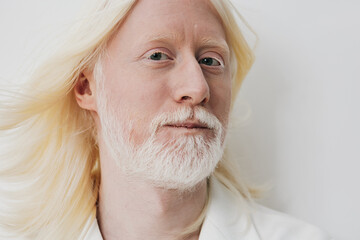 Portrait of a smiling man with long blonde hair and a beard against a clean, light background emphasizing serenity and calmness, suitable for personal or wellness themes