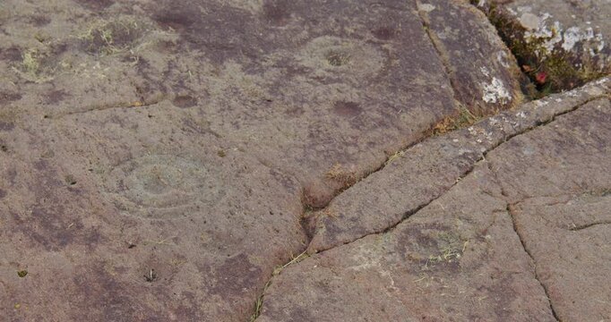 Slow zoom out of Baluachraig cup and ring carving in natural outcrop of level rock at Kilmartin glen