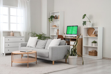 Fototapeta premium Modern computer with blank screen on table and laptop in living room