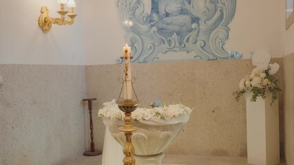 Quiet baptismal font with candle and floral decor inside church