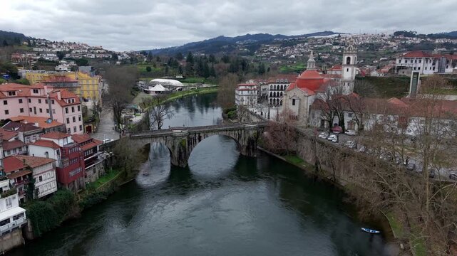 Amarante city under cloudy sky on Tamega river connecting Sao Goncalo catholic church area, Drone shot