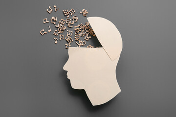 Paper human head with music notes on dark grey background. World Mental Health Day
