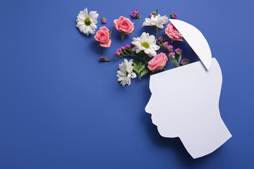 Paper human head with flowers on blue background. World Mental Health Day