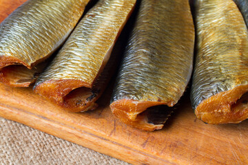Smoked Mathias fish on a wooden cutting board. Fresh, delicious smoked fish