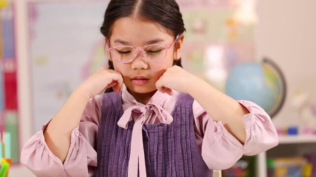Thoughtful Schoolgirl Adjusting Glasses While Concentrating in Classroom