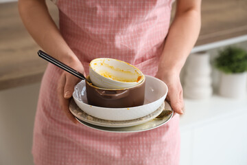 Beautiful young woman with dirty dishes in kitchen, closeup