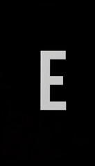 Obraz premium A crisp, white letter E stands out against a stark, minimalist black background , bold, graphic