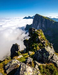 View of a mountain ridge above clouds. Sunny, blue skies with jagged peaks