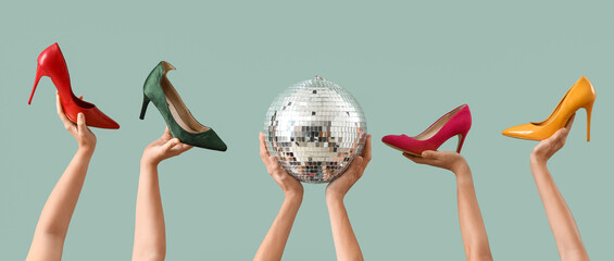 Female hands with disco ball and high heels on green background