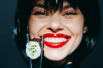 Smiling woman holding sushi with red lips in a stylish setting, showcasing Asian cuisine and...