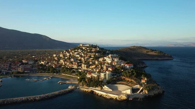 Aerial view of the picturesque seaside town of Paralio Astros, featuring traditional buildings, a harbor, and an open air amphitheater along the coastline of Greece.